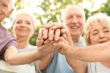 Group of elderly people putting hands together as symbol of unity