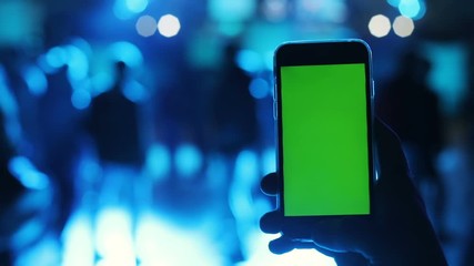 man hand holding using mobile smart phone blurred blue light people party trendy digital gadget tapping green screen pointing touching blank display corporate nightlife app store chatting mockup wifi