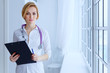 © lenblr - Portrait of serious female doctor with clipboard.