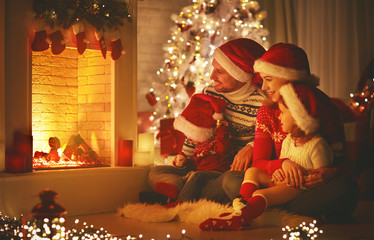 Wall Mural - happy family sitting by fireplace on Christmas Eve.