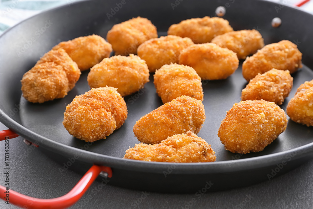 Delicious salmon croquettes on frying pan, closeup