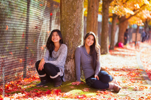 Plakat Biracial nastoletnia dziewczyna siedzi pod kolorowymi klonowymi drzewami w jesieni