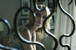 © MRoo1/Stocksy - Young pensive 18 year old girl sitting in her bedroom and seen through her bed post