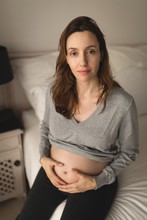 Pregnant Woman Sitting On The Bed At Home