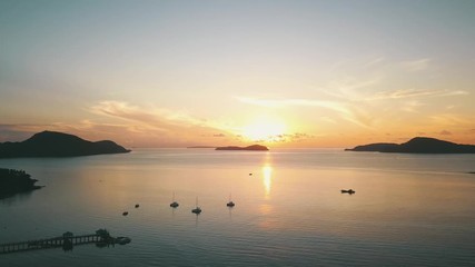 Wall Mural - sunrise bay in tropical island with reflected calm water and clouds aerial shot