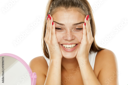 Plakat młoda uśmiechnięta kobieta napina twarz w dłoniach