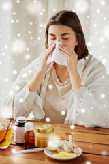 sick woman with medicine blowing nose to wipe