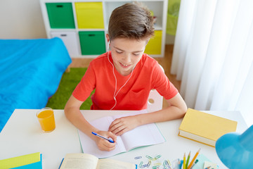 Wall Mural - happy student boy writing to notebook at home