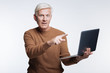 White-haired senior man pointing at laptop