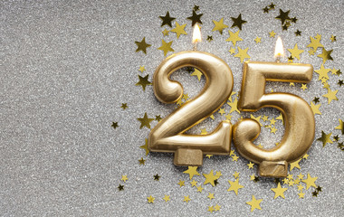 Number 25 gold celebration candle on star and glitter background