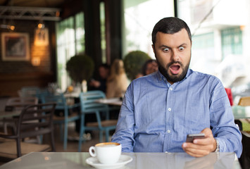 portrait of shocked man looking at phone