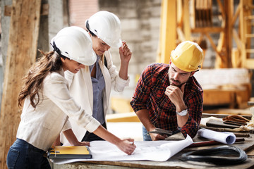 Two female inspectors and architects discuss with head engineer about construction project.