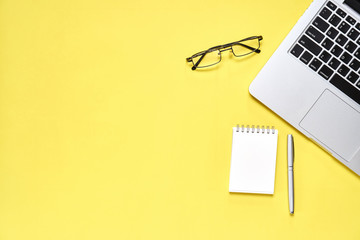 Fototapete - Top view, Modern workplace with laptop and notebook with pen placed on a pastel yellow background. Copy space suitable for use in graphics.