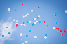Balloons Of Red Blue And White Colors Flying In The Blue Sky With Clouds