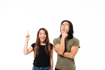 Poster - Portrait of a thoughtful smiling asian couple pointing finger up