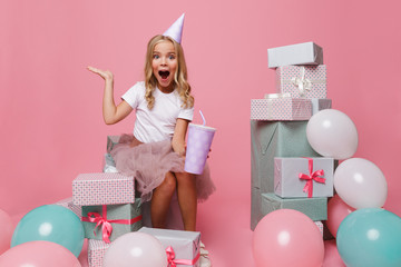 Wall Mural - Portrait of a cheerful little girl in a birthday hat