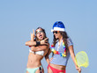 © kravik93 - Two girlfriends in a Santa hat and in the image of a pirate during a beach holiday. Christmas, holidays and people concept - friendship and fun
