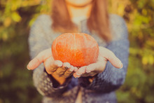 Young Woman Holding A Small Pumpkin In Hands