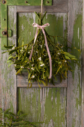 Fotografie, Obraz Christmas mistletoe plant with berries tied in a bunch with a white and red bow
