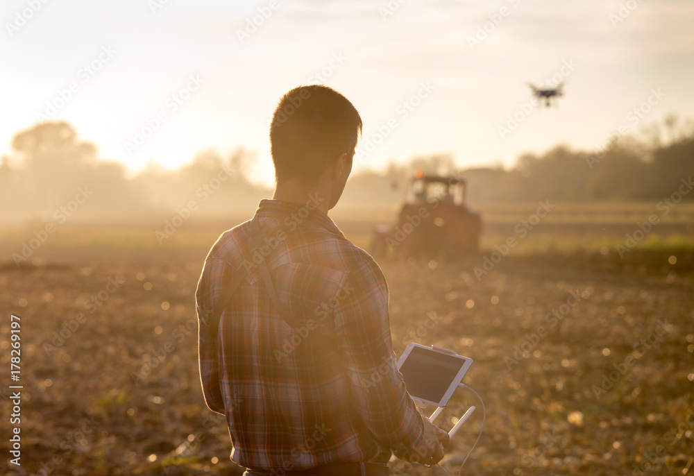 Farmer navigating drone above farmland - obrazy, fototapety, plakaty 