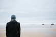 © Suzi Marshall/Stocksy - Man standing alone on the beach looking out to sea