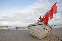 Fishing Boat With Red Flags At The Beach