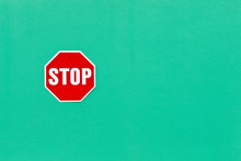 Image Of A Bright Red Stop Sign Against A Vibrant Green Wall