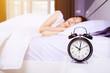 © geargodz - alarm clock on table and woman sleeping on bed in bedroom