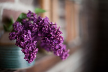 Blue Potter Vase Filled With Purple Lilacs Sitting On Wooden Ledge