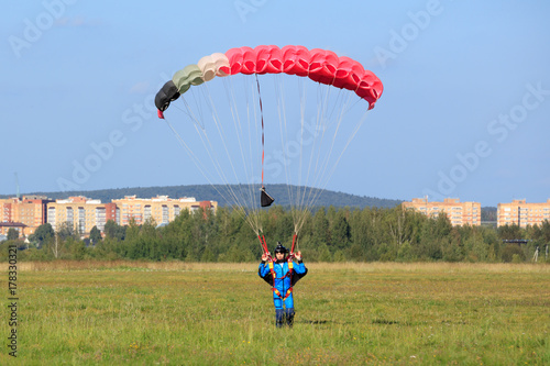 Zdjęcie XXL spadochroniarz wylądował na zielonym polu w letni dzień na tle miasta