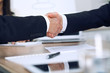 © rogerphoto - Close up of business people shaking hands at meeting or negotiation in the office. Partners are satisfied because signing contract