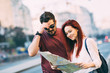 © minastefanovic - Young couple traveler lost in the city using map