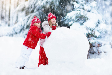 Wall Mural - Kids building snowman. Children in snow. Winter fun.