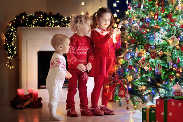 Wall Mural - Children at Christmas tree. Kids at fireplace on Xmas eve