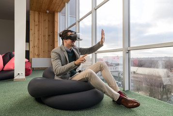 Canvas Print - Business Man Wear Digital Glasses Hold Hand Virtual Reality Sit in front Panoramic Window Businessman Coworking Center Office Interior