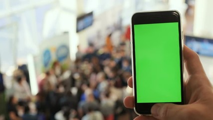 male man hand holding using smartphone typing swapping scrolling blank display mockup green screen chroma key blurred people conversation hall background tapping message email network online IT app