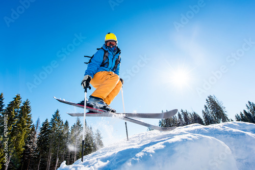 Obrazy Narciarstwo  niski-kat-strzalu-narciarza-w-kolorowe-biegu-skoki-w-powietrzu-podczas-jazdy-na-nartach-na-zboczu-copyspace