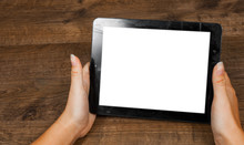 Woman's Hand Holding Black Tablet Pc With Blank White Screen On A Wooden Background. With Copy Space. Top View