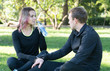 © Oleg - Young happy sporty couple sitting on a meadow in a park after training, drink water