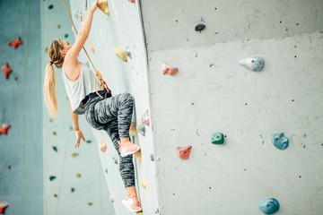 Free climber young woman climbing artificial boulder indoors