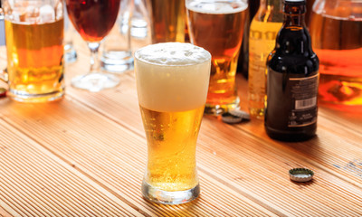 Wall Mural - A wooden pub counter, focus on a full frosty glass of beer