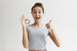 Positive human emotions, reaction, gestures and body language. Happy ecstatic young woman with hair bun totally agrees with something, showing ok sign and thumbs up, keeping mouth wide opened