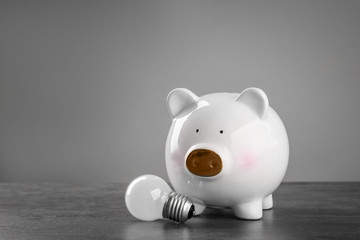 Wall Mural - Cute piggy bank with lamp on table against grey background