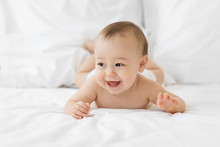 Smiling Baby Laying On Belly On White Bed