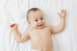 © Lisa Tichané - Happy baby lying on back on white bed
