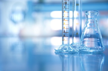 Wall Mural - glass flask with cylinder in blue science laboratory background