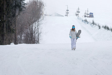 Wall Mural - Young girl snowboarder goes towards camera on snowy mountain in the forest