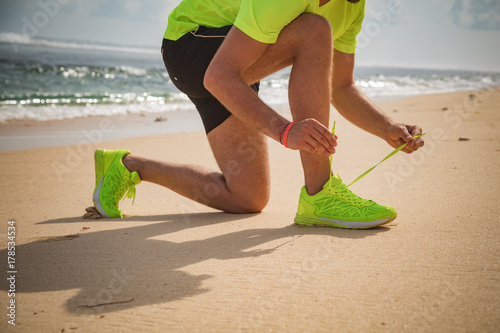 Plakat Wiąże jogging / działający buty na tropikalnej piaskowatej plaży blisko morza / oceanu.