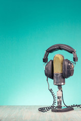 Wall Mural - Retro studio ribbon microphone and headphones on table front gradient mint green wall background. Vintage old style filtered photo