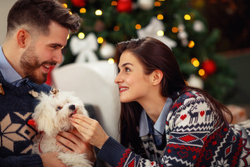 Wall Mural - Woman with husband at home with cute dog celebrating Christmas eve